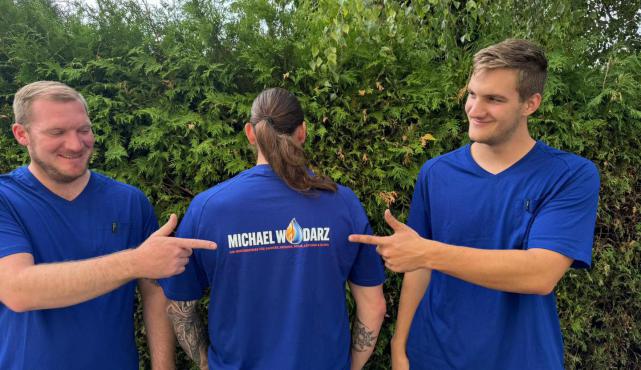 Mitarbeiter des Meisterbetriebs Michael Wodarz in Gröbenzell zeigen stolz das Firmenlogo – Handwerk mit Herz, Qualität und Teamgeist